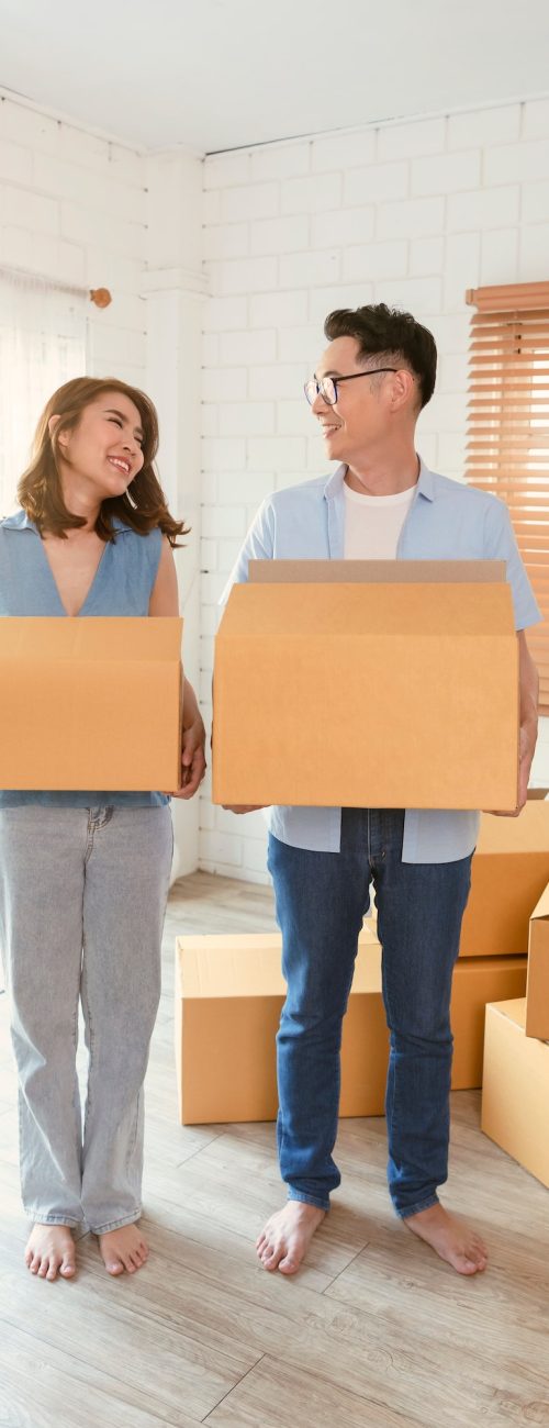 Happy Asian couple holding cardboard box go into new home. Relocation concept Happy Asian couple holding cardboard box go into new home. Relocation concept